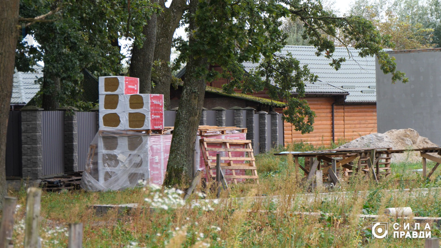 Паркан, що обгороджує лісомисливське подвір’я Богдана Колісника. Поруч нього розміщені дерев’яні палети і блоки скловати, що використовуються для будівництва котеджів